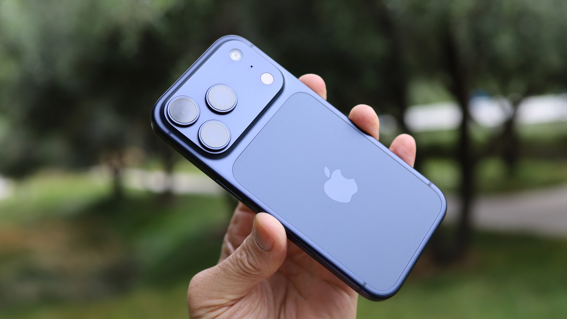 iPhone 18 Pro de color azul oscuro sostenido en la mano, destacando el nuevo diseño de cámara cuádruple en un módulo horizontal.